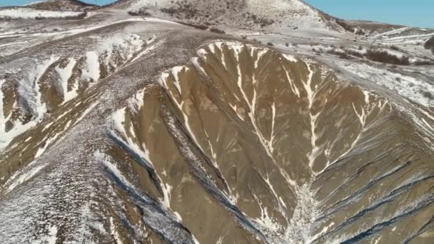 Vista aérea sobre laderas de montañas marrones cubiertas de nieve contra el cielo azul claro. Le dispararon. Hermoso paisaje . — Vídeos de Stock