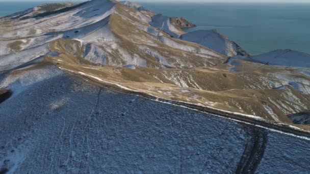 Vue aérienne de la chaîne de montagnes et de la route en hiver près de la mer contre un ciel nuageux bleu. Fusillade. Beau paysage . — Video