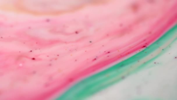 Nahaufnahme bunter rosa und grüner verschwommener Farbflecken auf einer milchigen Oberfläche. farbenfroher Hintergrund. — Stockvideo