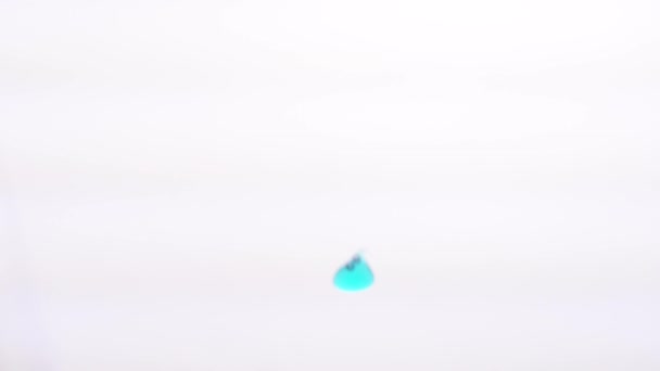 Blue gel drops falling in water on a white background. Close-up. — Stock Video