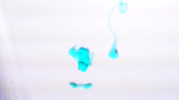 Primo piano del getto di gel blu che cade in acqua su uno sfondo bianco. Struttura dell'acqua . — Video Stock