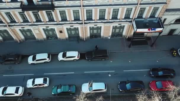 Luchtfoto van de straat met lopen mensen, huizen en geparkeerde auto's, in de buurt van de stoep. Ochtend in de stad. — Stockvideo