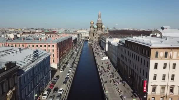 Blick auf städtische Gebäude, Autos und Menschen am Ufer des Peterburger Kanals mit einer Kathedrale im Hintergrund. schöner sonniger Tag. — Stockvideo