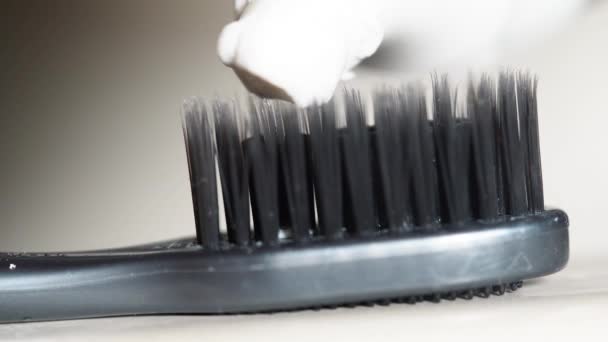 Gros plan de la brosse à dents grise avec du dentifrice sur fond gris. Concept de santé . — Video