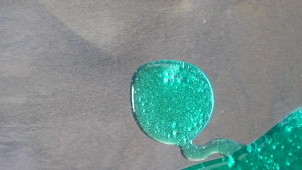 Close-up van gemorste turquoise gel op een grijze oppervlak. Kleurrijke textuur. — Stockvideo