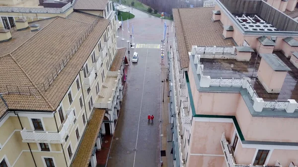 Top view of two people walking in rain. Two people go to red raincoats in rain on wet street of old town