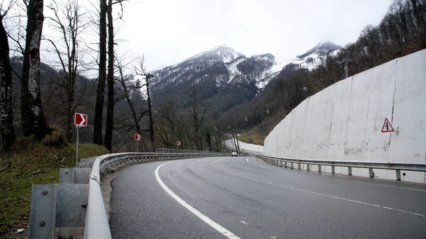 Tourner sur la route de campagne dans la zone de montagne forestière. Trafic passant voitures montagne route sinueuse à travers la forêt sur fond de téléphérique par temps nuageux — Photo