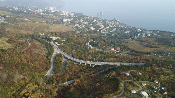 一个美丽的海湾的空中景观与森林和丘陵, 小镇, 和高速公路。拍摄。美丽的雾蒙蒙的秋黄田野, 高速公路, 和沿海城市附近的海. — 图库照片