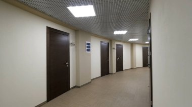 Boş, açık bej ile koridor yuvarlak duvarlar ve kapalı, koyu kahverengi kapılar. Ofis Binası içinde yanan bir koridor boyunca kapalı kapılar.