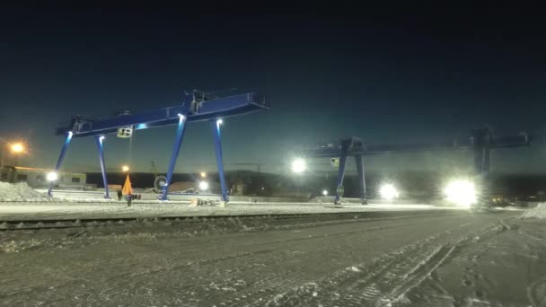 Grandes grúas pórtico en la zona idustrial durante el proceso de trabajo, lapso de tiempo. Grúas de carga cerca de almacenes en la noche de invierno . — Vídeo de stock