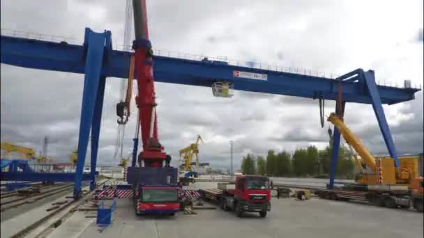 Grandes grúas pórtico en la empresa de transporte logístico sobre fondo gris, cielo nublado. Grúas pórtico, grúas de camiones y personas que realizan trabajos de carga, lapso de tiempo . — Vídeo de stock