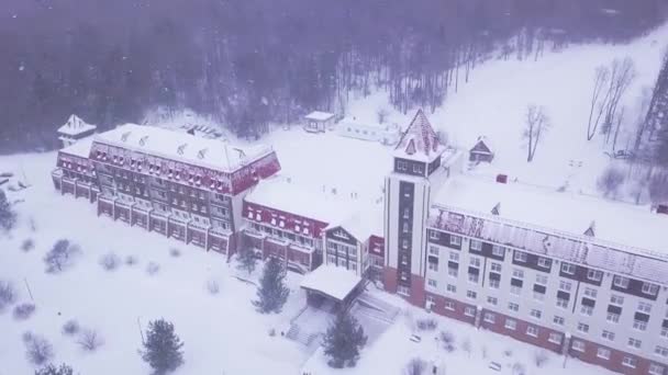 Toevlucht in het bos tijdens de sneeuwval. Clip. Rode geïntegreerde resort in stijl van kasteel omringd door bossen in besneeuwde bewolkt weer — Stockvideo