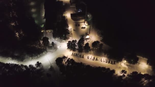Předměstí s lesy v zimě v noci. Klip. Pohled shora příměstské podniku s trubkami a zasněžené trati osvětlují lucerny v lesnaté oblasti v noci — Stock video