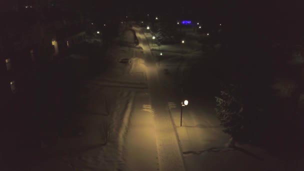 Городская улица с заснеженной тропой, освещенной фонарями ночью. Клип. Прекрасная ночная тьма со светлыми фонарями освещает тропинку возле домов в зимний снегопад — стоковое видео