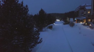 Sokak ışıkları yolu kışın Park'ta yürüyordunuz insanlarla aydınlatmak. Küçük. Güzel kış akşam insanlarla kar yağışı ışıklı resort parkta yürüyüş
