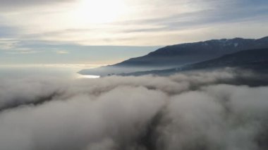 Alçak bulutlar ve mavi gökyüzü ile dağ manzarası en iyi görünümü. Vurdu. Güzel manzara parlak güneş ışığının yansıması ile deniz ufuk karşı dağ bulutlar çıkıntılı