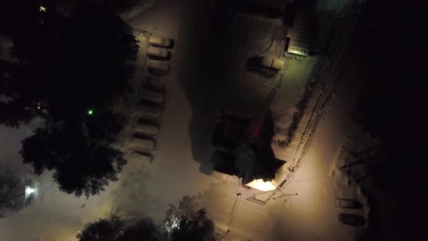 Вид зверху на автостоянку вночі взимку. Кліп. Міська парковка зі сніговим покриттям автомобілів і яскравими вогнями вночі взимку — стокове відео