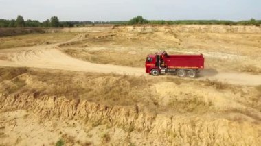Anten arka planda gri gökyüzü ve ağaçlar karşı kum pistte hareketli kırmızı kamyon görüntüleyin. Yukarıdan güzel manzara.