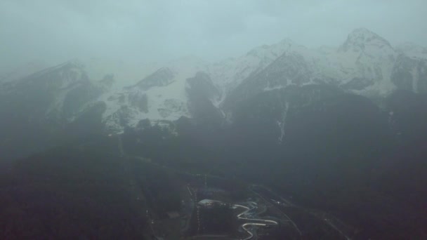 Skigebiet am Fuße des Berges bei bewölktem Wetter. Blick von oben auf den Ort am Berg im Nebel bei bewölktem Wetter am Abend — Stockvideo