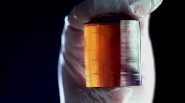 Yanık turuncu maden parçası. Siyah arka plan üzerine işlenmiş sarı maden parçası holding eldivenli eller Close-Up