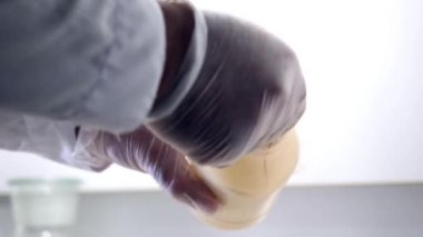 Laboratuar işçisi pullarla. Kimyager giyen eldiven konservesi üzerinden Close-Up kimyasal laboratuvar olarak tartmak için birim cam fincan bataklık koyar