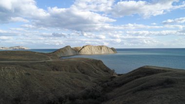 Kaya, mavi okyanus ve bulutlu gökyüzü arka plan, hava Vadisi üzerinde yaz günbatımı. Vurdu. Yüksek, büyük dağ mavi su ve yeşil alan ile güzel deniz manzarası.