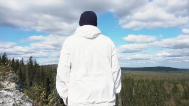 Dağ orman manzarası tarafından tek başına duran turist. Güneşli bir gün, arka plan ormanın ufukta için arkadan görünüm bir kaya tırmanışı ve arıyorsunuz. Ufuk için arıyorsunuz