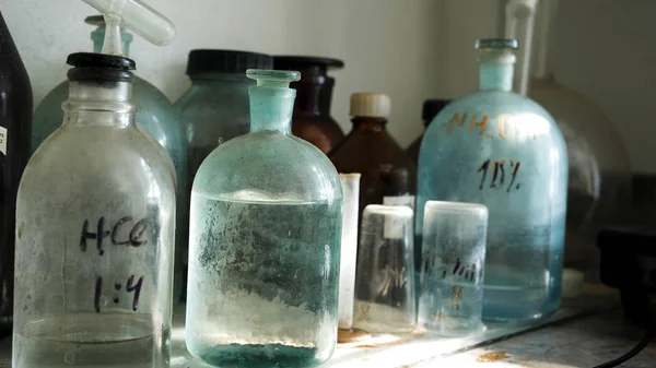 Laboratorio di chimica con soluzioni acide in vecchie fiaschette di vetro. Close up per la tavola con soluzioni chimiche in laboratorio, concept scientifico . — Foto Stock