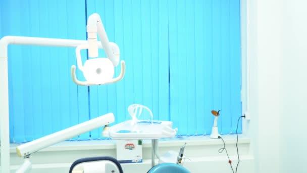 Dental chair and other accessories used by dentists in blue, medic light, medicine concept. Modern dental equipment in the empty cabinet. — Stock Video