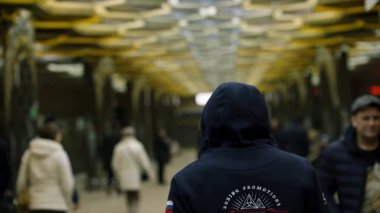 Kalabalık istasyonunda, direnç kavramı yürürken üzerinde dikiz koyu mavi kapüşonlu olan bir adam. Adam geri önünde metro birçok kişi için yakın çekim.
