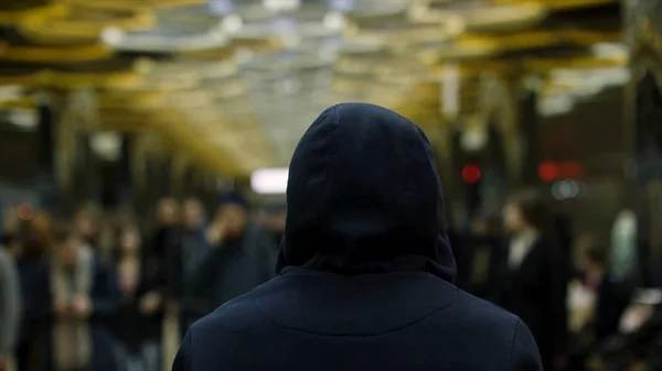 Вид сзади на человека в темно-синей толстовке, стоящего перед толпой на вокзале, концепция сопротивления. Закрыть для человека перед многими людьми в метро . — стоковое фото