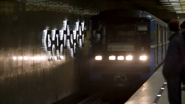 Viene el tren y la gente lo espera en la estación de metro. Transporte de metro que llega a la estación de metro con muchos pasajeros esperándolo . — Foto de Stock