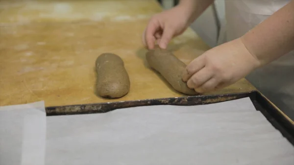 Zbliżenie się do rąk baker, przygotowanie surowego żyta na bochenek, jedzenie koncepcja. Kobieta ręce Dokonywanie bagietki z żyta surowego ciasta onwooden zarządu w piekarni. — Zdjęcie stockowe