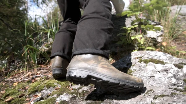 Cerrar para senderismo botas de goma en acción en un camino rocoso. Hombre haciendo pasos para subir una montaña en un día soleado . — Foto de Stock