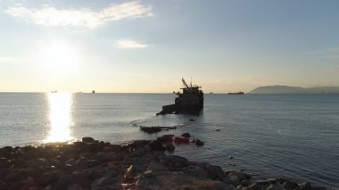 Hava günlük güneşlik karşı kayalık sahil boyunca harap gemi için. Vurdu. Deniz kıyısında büyük dağ ve mavi gökyüzü arka plan yakınındaki gemi batırıldı.
