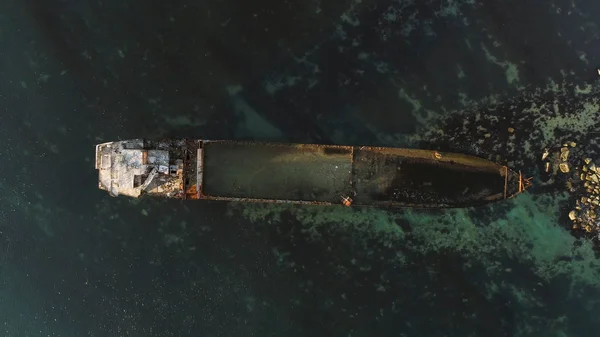 Vista aérea superior para el barco naufragado a lo largo de la costa rocosa en agua azul. Le dispararon. Antiguo barco hundido cerca de la orilla del mar, vista desde arriba . —  Fotos de Stock