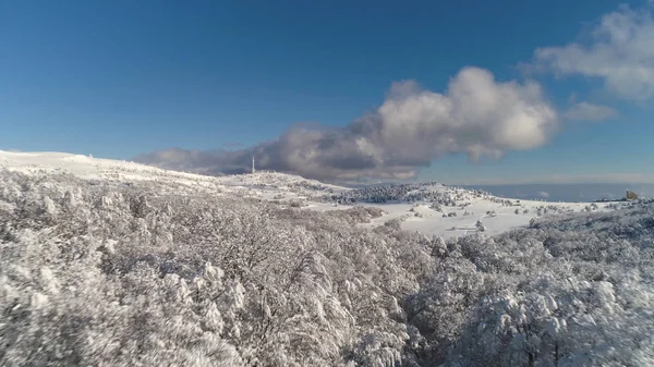 Fantastische Winterlandschaft mit hohen Bergen und verschneiten Wäldern vor bewölktem, blauem Himmel. Schuss. sonniger Tag in Weiß, winterliche Felsen und schneebedeckte Bäume gegen strahlenden Himmel. — Stockfoto