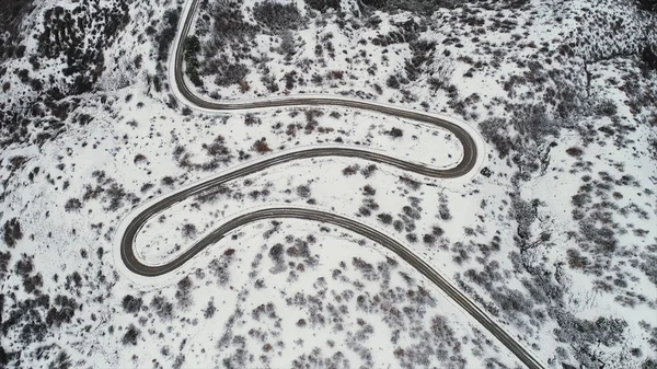 Κορυφαία Αεροφωτογραφία του χιονιού ορεινό τοπίο με δέντρα, δρόμο και γαλάζια θάλασσα. Βολή. Όμορφο τοπίο του χειμώνα δρόμου σε χιονισμένα πεδία κοντά σε ακτές. — Φωτογραφία Αρχείου