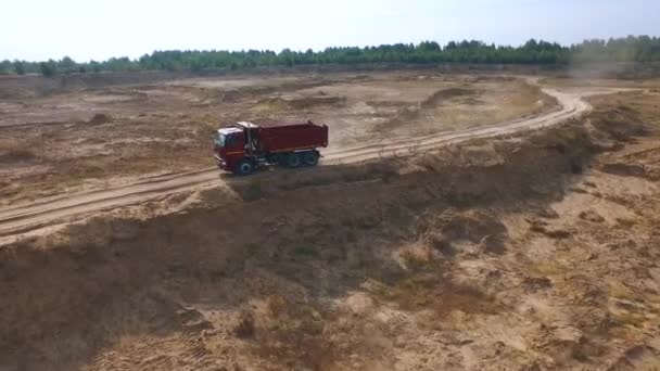 Letecký pohled na prázdné červené sklápěč pro písek dodávku pohybující se na pískové trati s pole a nebe na pozadí. Scénu. Terénní automobil. — Stock video