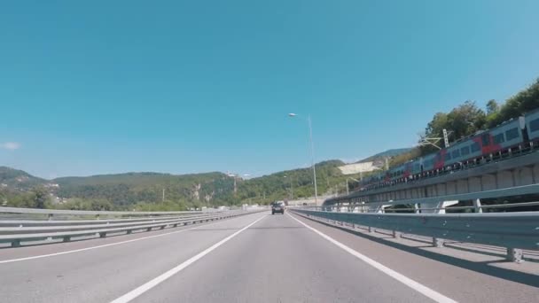 푸른 하늘과 산에 대 한 철도 지나가는 기차 근처 고속도로에서 자동차에서 보기. 장면입니다. 소 치, 크라스노다르 지역, 러시아. — 비디오