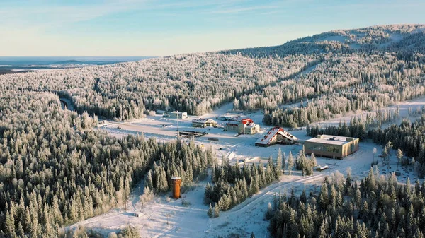Una hermosa antena una montaña nevada en la estación de esquí en el fondo del cielo azul. Filmación. Día soleado de invierno en bosques de pinos verdes y laderas nevadas de los Alpes con funicular . — Foto de Stock