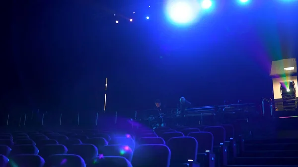 Gelap, ruang bioskop kosong dengan kursi nyaman di cahaya biru, proyektor, dan lampu sorot terang. Tutup baris kursi di bioskop. . — Stok Foto