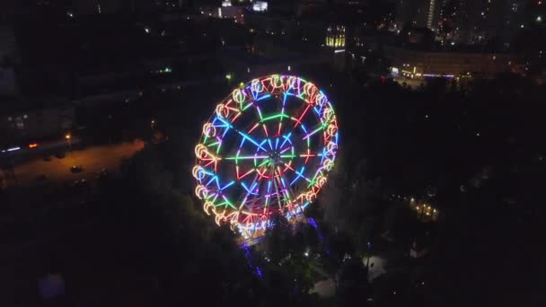 Amusement Park Aerial Shot Night City Lights. Clip. Aerial view moving front of beautiful Ferris wheel in the background lighting up the summer night — Stock Video