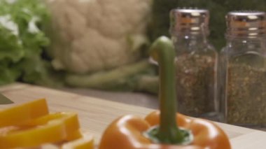 Baş kesme sarı bir ahşap tahta üzerinde profesyonel bir bıçak ve büyük bir beceri ile biber. Sahne. Şef salata sağlıklı yemek yapma ve dolmalık biber kesme tahtası üzerinde doğrama yakın çekim