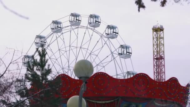 Неподвижное колесо обозрения в парке развлечений на сером фоне неба. На складе. Парк развлечений осенью без людей . — стоковое видео
