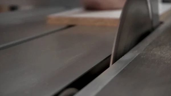 Κοντινό πλάνο για ξυλουργό χρησιμοποιώντας κυκλικό πριόνι για ξύλινη σανίδα κοπής στο εργαστήριο. Footage.Male εργαζόμενος περικόπτει την άκρη της σανίδας ασφαλίζει με ένα πριόνι. — Φωτογραφία Αρχείου
