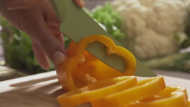 Jefe de corte de pimientos amarillos en una tabla de madera con un cuchillo profesional y una gran habilidad. Escena. Primer plano del jefe haciendo ensalada comida saludable y picando pimiento en la tabla de cortar — Vídeos de Stock