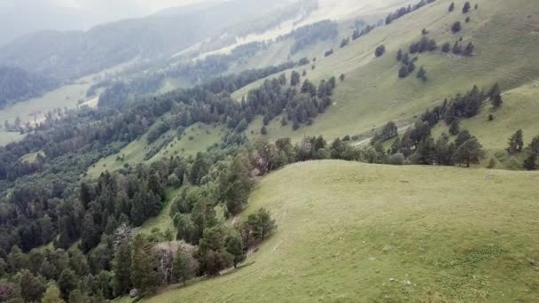 Luchtfoto. Vlucht over een groene grazige rotsachtige heuvels. Vliegen over de hoge bergen in prachtige wolken — Stockvideo