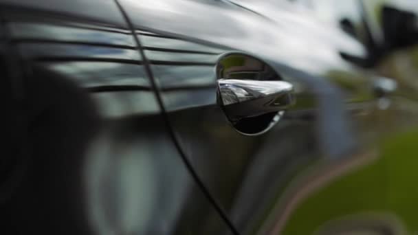 Puerta del coche manija de cerca. La puesta de sol se refleja en el coche nuevo. Puerta de coche negro de cerca — Vídeos de Stock