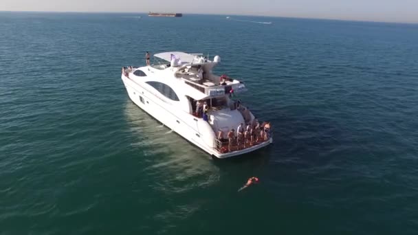 Vista aérea de iate ou barco com pessoas cruzando em mar aberto. Estoque. Vista aérea de um iate em um mar cristalino, com pessoas prontas para mergulhar no mar aberto — Vídeo de Stock